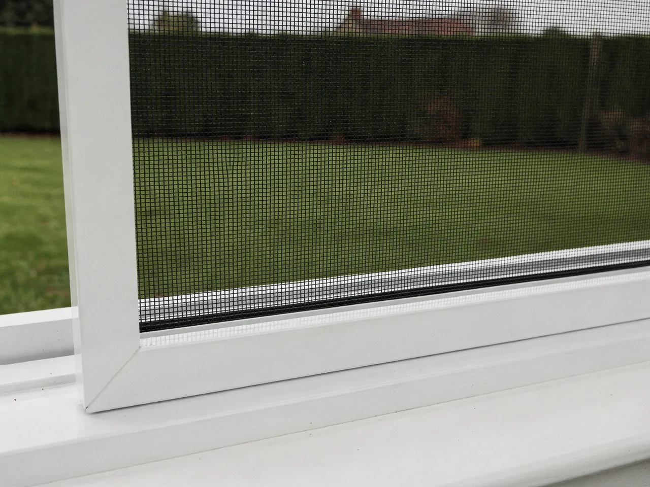 Insektenschutzrahmen aus weißem Aluminium in einer Fensterlaibung, Nahaufnahme des Gewebes